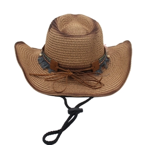 Detail of woven straw cowboy hat with ethnic style ribbon, gray fringe and wooden beads