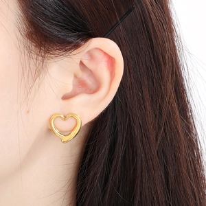 Close-up of a model wearing a minimalist gold hollow heart earring in a stylish look