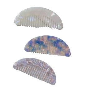 Three acetate wide-tooth hair combs with marble textures shown from top view