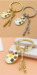 Detailed close-up of gold and silver art palette keychains with enamel paint drops
