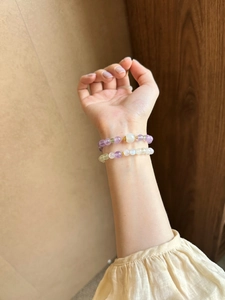 Detailed shot of amethyst and green crystal beaded bracelets worn on a model's wrist