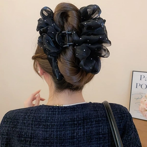 Detail of a large black bow hair claw clip with pearls on mesh for thick hair