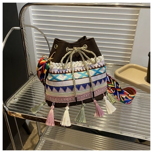 Detail of colorful geometric embroidery and multi-color tassels on a woven bucket bag