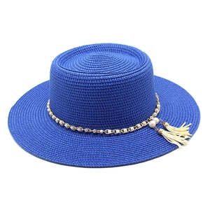 Détail d'un chapeau de paille bleu roi avec chaîne dorée, perles et glands élégants