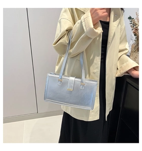 Silver metallic shoulder bag styled with a beige coat in a minimalist modern setting