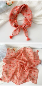 Detail of coral pink floral cotton scarf featuring delicate tassels and sheer texture