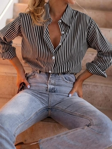 Detailed view of women's long sleeve blouse with black and white vertical stripes