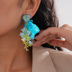 Detail of blue chiffon heart earrings with layered beads and tassels on a model