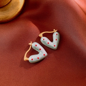 Détail de boucles d'oreilles cœur vert menthe à pois rouges et bords dorés