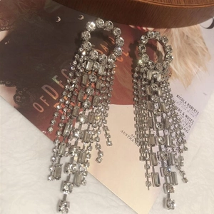 Silver geometric hoop earrings with cascading crystal tassels on fashion magazine background