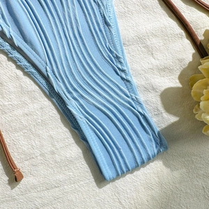 Detail of light blue pleated bikini fabric with wavy texture and side tie string