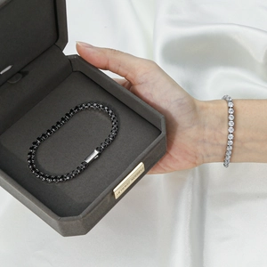 Detailed close-up of silver and black tennis bracelets on white silk and jewelry box
