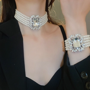 Detail view of multilayer pearl necklace and bracelet with large crystal embellishment