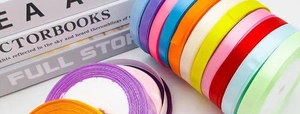 Close-up of stacked colorful 1cm satin ribbon rolls for gift wrapping and DIY crafts