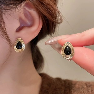 Detailed view of vintage waterdrop earrings with gold textured borders and black stones