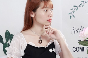 Model wearing a gold stainless steel necklace with a round shell pendant on white ruffles