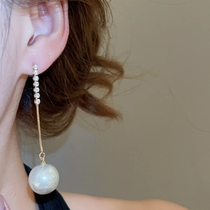 Close-up of elegant long pearl earrings with sparkling crystals on a female model