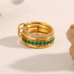 Detailed close-up of 18K gold-plated four-layer stacked ring set with emerald green gems
