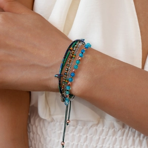Detail van de gelaagde armband met turquoise glaskralen en verstelbaar trekkoordsluiting