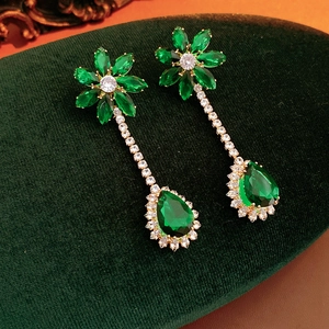 Detail of green zircon flower earrings with sparkling water drop pendants on velvet