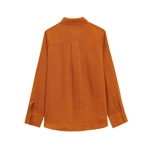 Dettaglio del retro di una camicia in lino arancione ruggine con piega e bordo curvo
