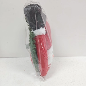 Detail of plush Santa tree hugger in clear packaging with red body and green pine accents