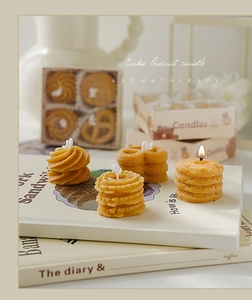 Vista detallada de velas aromáticas con forma de galleta sobre libros, tonos crema