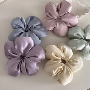 Macro detail of five assorted silk texture floral scrunchies in pastel spring colors