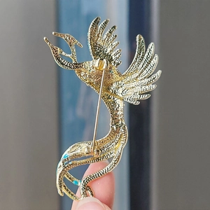 Back view of a gold enamel phoenix brooch showing the secure pin fastener and metal finish