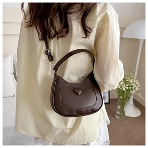 Detail of a dark brown hobo bag featuring a 3D heart relief and adjustable shoulder strap