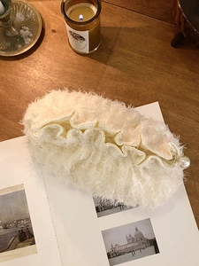 Détail d'une trousse à maquillage en peluche crème avec fermeture éclair en perle