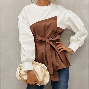 Detail of elegant brown and white geometric patchwork blouse with puff sleeves and belt