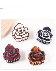 Detailed view of four rose flower hair claw clips in assorted colors and petal textures
