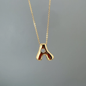Detailed view of polished golden letter A pendant on a delicate link chain necklace