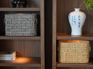 Detail of hand-woven rectangular rattan storage basket with side handles on a bookshelf