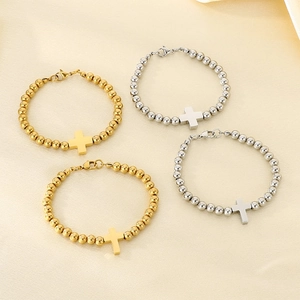Detail of 6mm beaded cross bracelets in gold and silver finish on a textured background