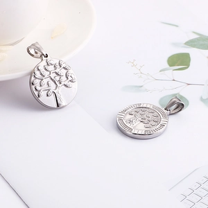 Silver tree of life stainless steel pendants on a white table with natural lighting