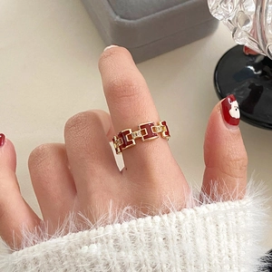 Close-up of gold plated H-letter ring with red enamel and white zircon stones