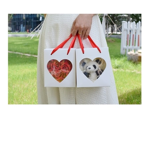 White heart window gift box with red ribbon handles and plush panda inside