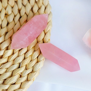 Polished double-pointed rose quartz crystal columns on a woven mat and fabric
