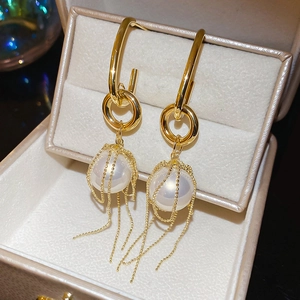 Detail of elegant gold tassel earrings with pearls on beige velvet jewelry box background