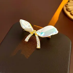 Detailed view of gold butterfly brooch with iridescent shell wings and sparkling zircon