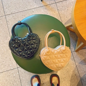Detail view of heart-shaped quilted jelly bags in black and beige with top handles
