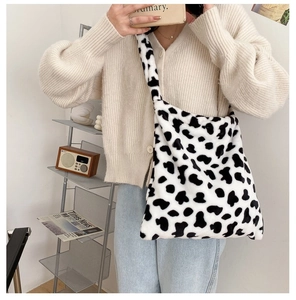 Detail of soft faux fur crossbody bag featuring stylish black and white cow print texture