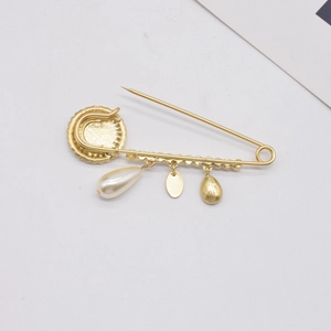 Vintage baroque gold brooch with pearls and metal tassels on a clean white background
