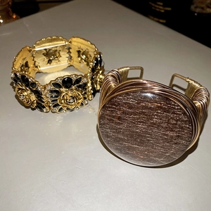 Close-up of golden floral bracelet with black gems and wire-wrapped stone bangle
