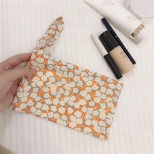 Floral cotton pouch with zipper and wrist strap for makeup storage in warm orange