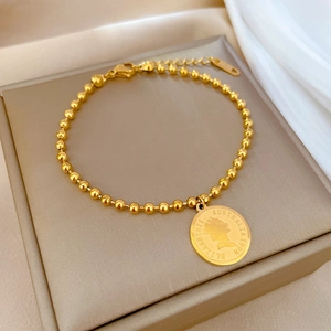 Macro shot of titanium steel bead bracelet with a vintage Elizabeth II gold coin pendant