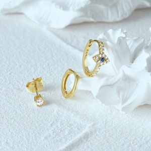 Detail of gold S925 silver evil eye earrings set featuring blue stone and zirconia studs