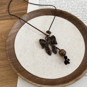 Détail du collier avec pendentif nœud imprimé léopard vintage et cordon marron